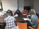 Zdjęcie 2: Grupa osób siedząca i pisząca przy stole podczas zajęć grupowych pod nazwą „KOMPENDIUM  RYNKU PRACY"