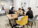Zdjęcie 1: grupa osób siedząca przy stole podczas warsztatów pod tytułem: „Ucz się, zarządzaj, zarabiaj – wiedza Twoim atutem"