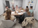 Zdjęcie 2: Grupa osób siedząca przy stole podczas zajęć grupowych pod nazwą „Jak i gdzie szukać pracy?"